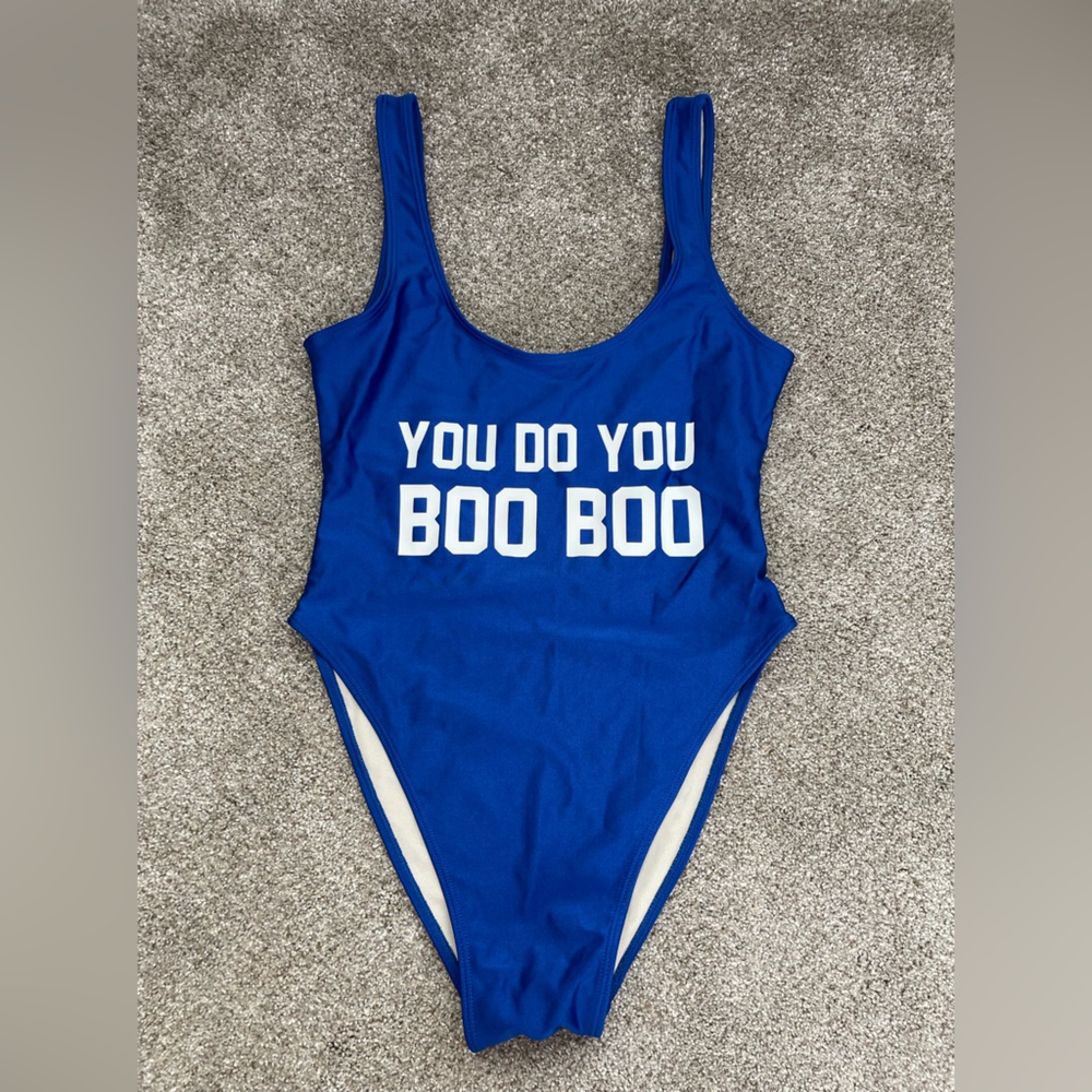 Blue one piece swimsuit with saying, “you do you boo boo,” in white letters.